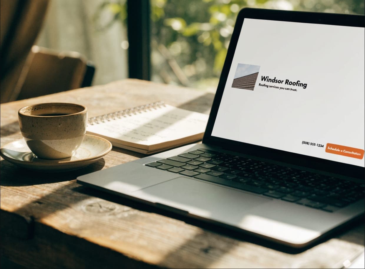 A laptop on a wooden desk showing a single-service website landing page for a roofing business